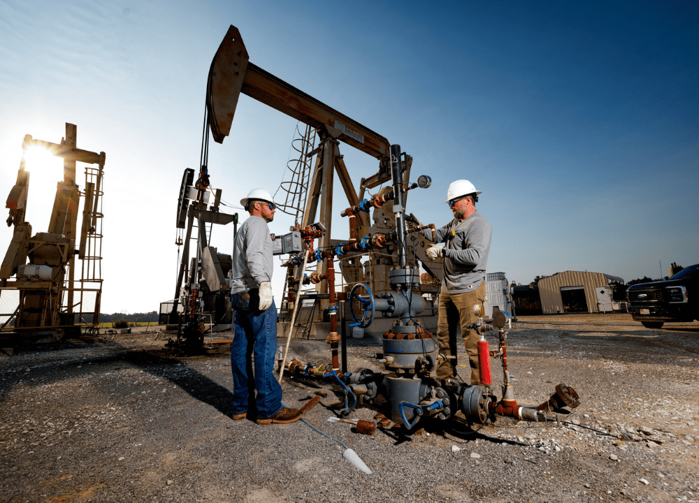 Oilfield workers wearing safety gear and reviewing plunger retrieval protocols