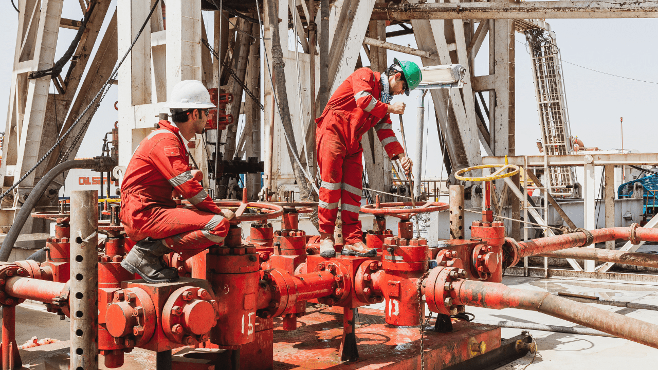 oilfield well site with workers inspecting equipment